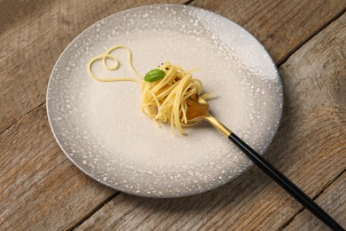 Photo of Heart made with spaghetti and fork on wooden table