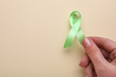 Photo of World Mental Health Day. Woman holding green ribbon on color background, space for text