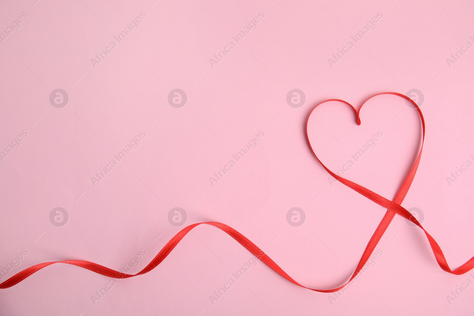 Photo of Heart made of red ribbon on pink background, top view with space for text. Valentine's day celebration