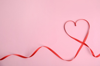 Photo of Heart made of red ribbon on pink background, top view with space for text. Valentine's day celebration