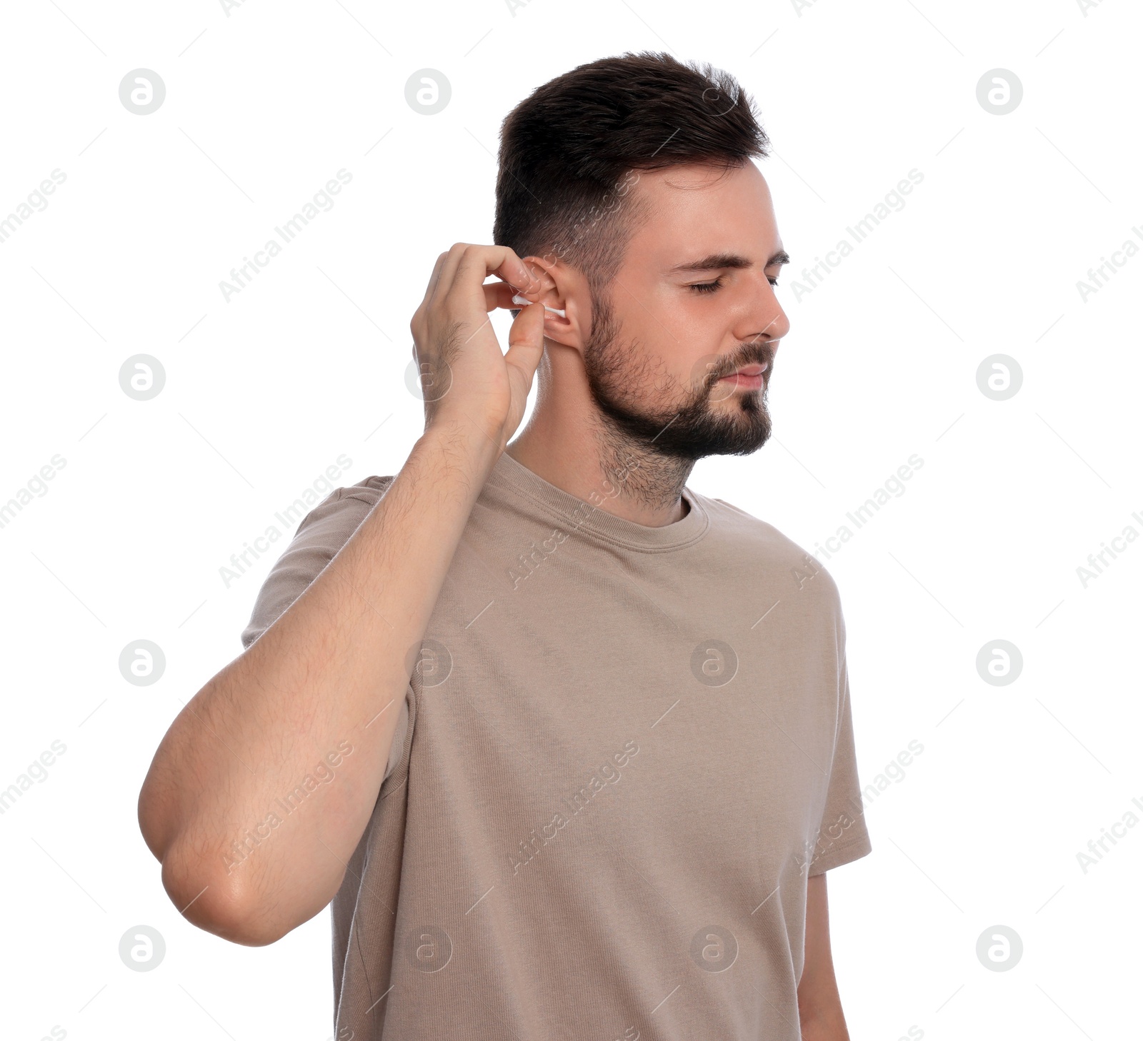 Photo of Young man cleaning ear with cotton swab on white background