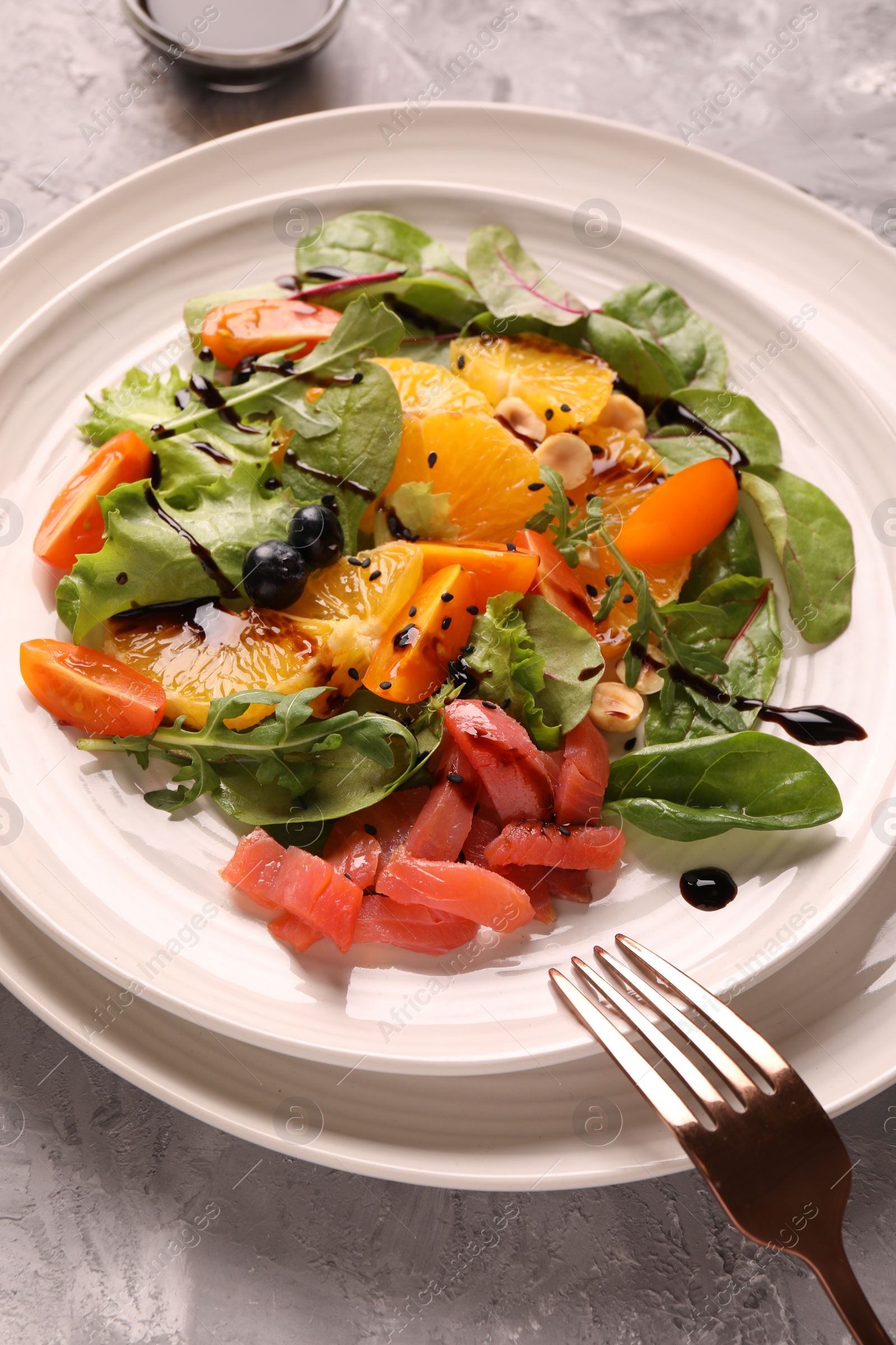 Photo of Delicious salad with salmon served on gray table, closeup