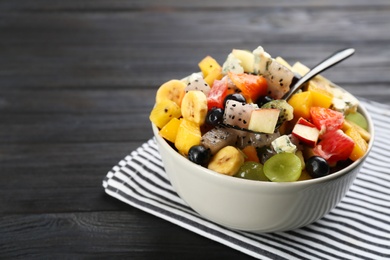 Delicious exotic fruit salad on black wooden table, closeup. Space for text