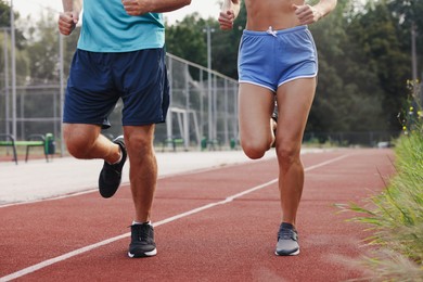 Healthy lifestyle. Sporty couple running at stadium, closeup