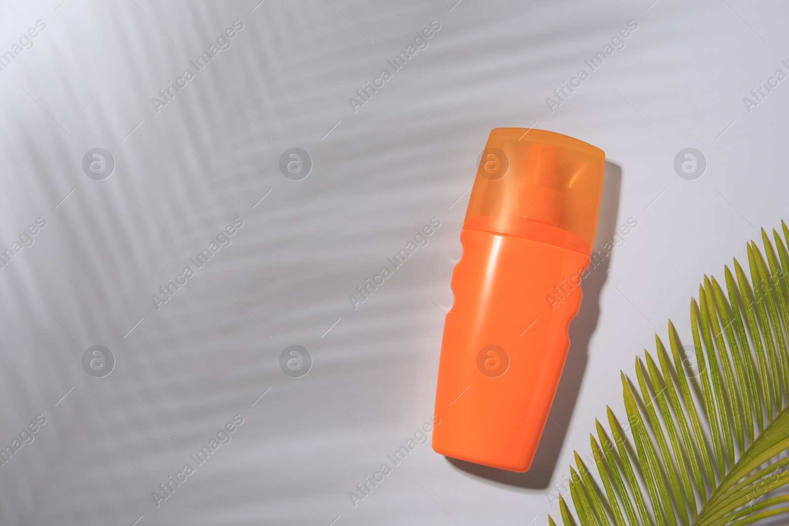 Photo of Sunscreen and tropical leaf on white background, flat lay and space for text. Sun protection care