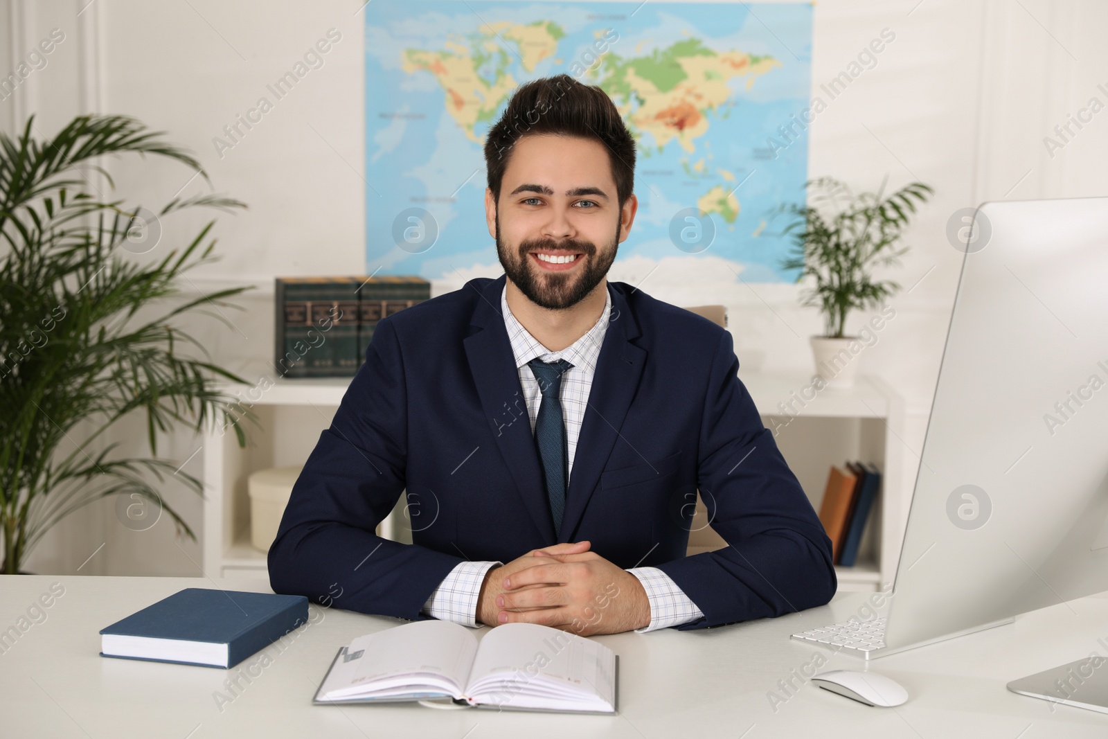 Photo of Happy manager with notebook sitting at desk in travel agency