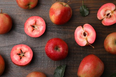 Photo of Tasty apples with red pulp and leaves on wooden table, flat lay