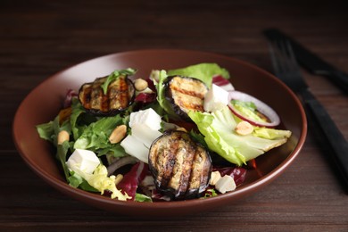 Photo of Delicious salad with roasted eggplant, feta cheese and arugula on wooden table