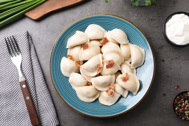 Plate of tasty cooked dumplings served on stone surface, flat lay