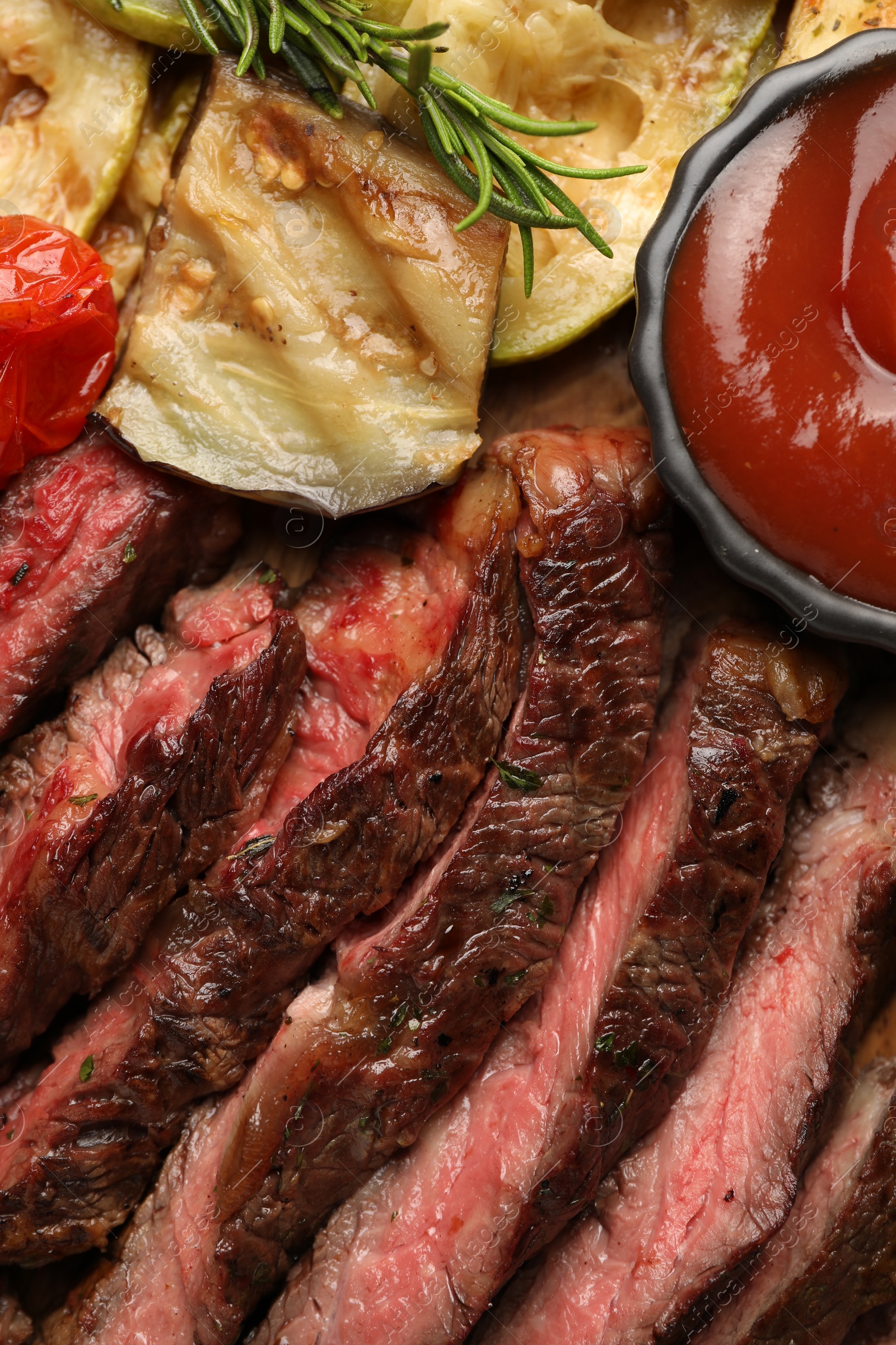 Photo of Delicious grilled beef with vegetables, spices and tomato sauce on table, top view