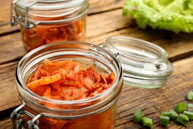 Photo of Delicious kimchi with Chinese cabbage and ingredients on wooden table, closeup