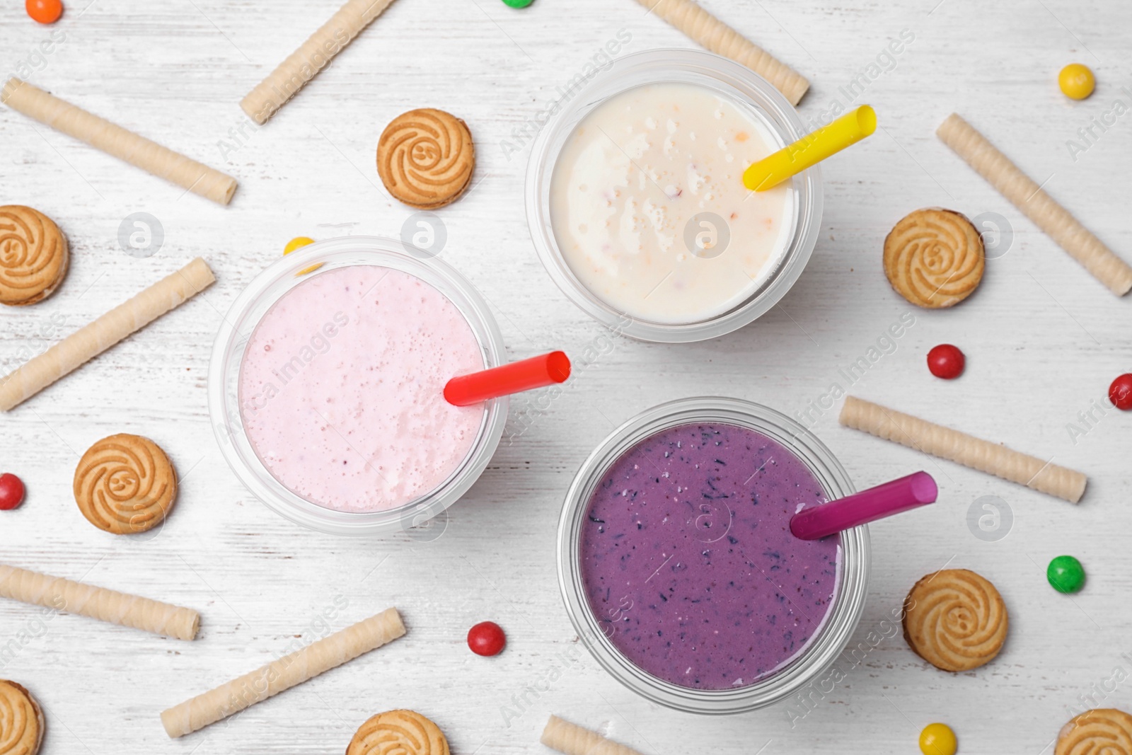 Photo of Flat lay composition with tasty milk shakes on white wooden table