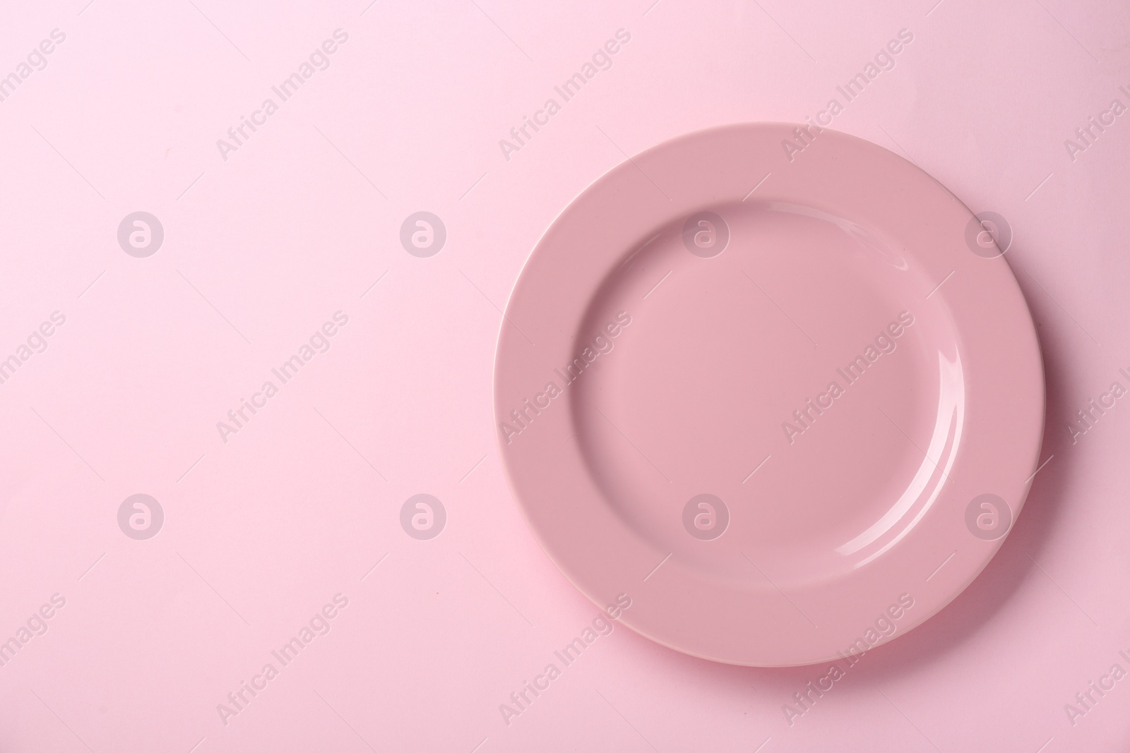 Photo of Clean plate on pink background, top view. Space for text