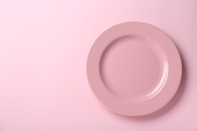 Photo of Clean plate on pink background, top view. Space for text