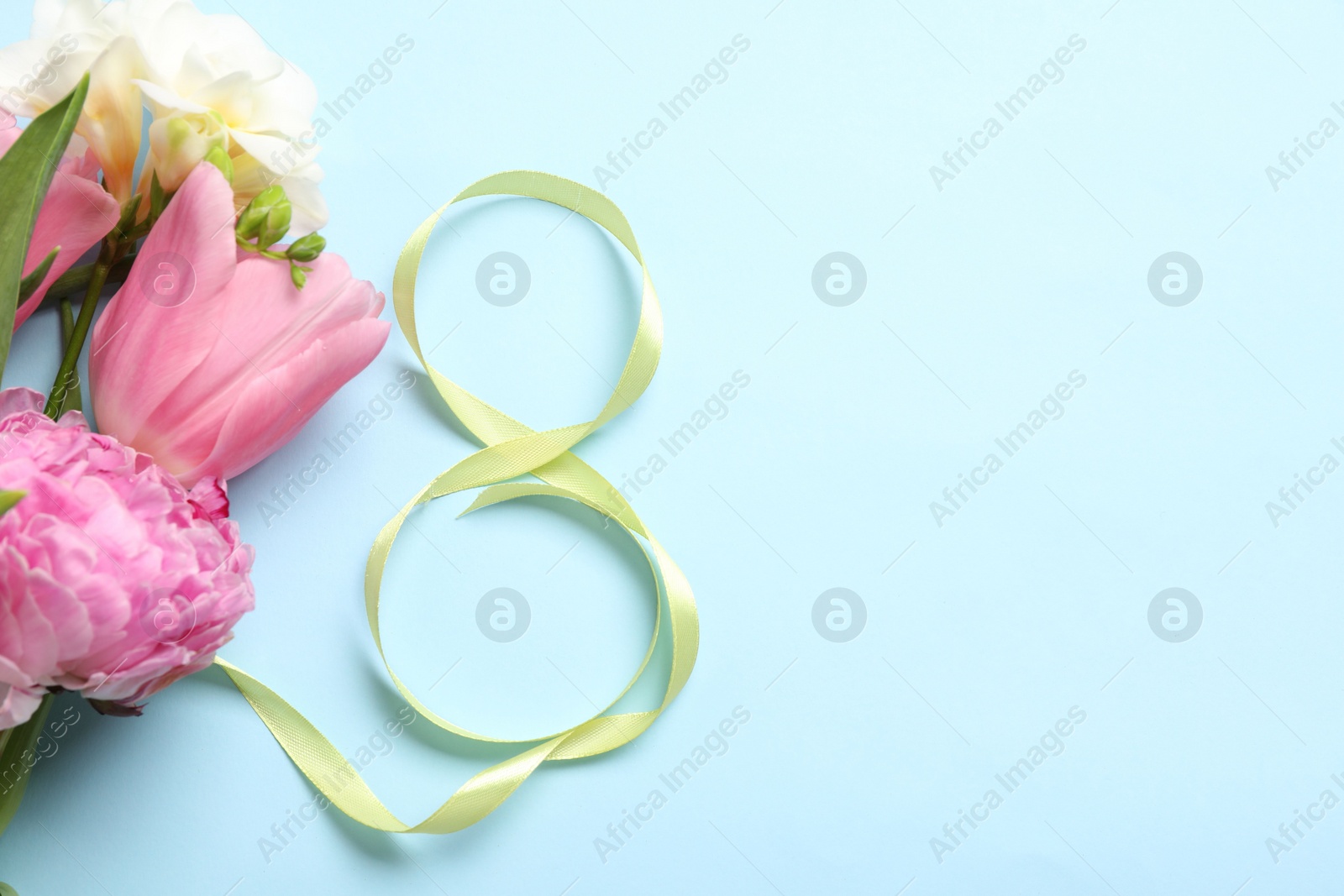 Photo of 8th of March greeting card design with green ribbon, beautiful flowers and space for text on light blue background, flat lay. International Women's day