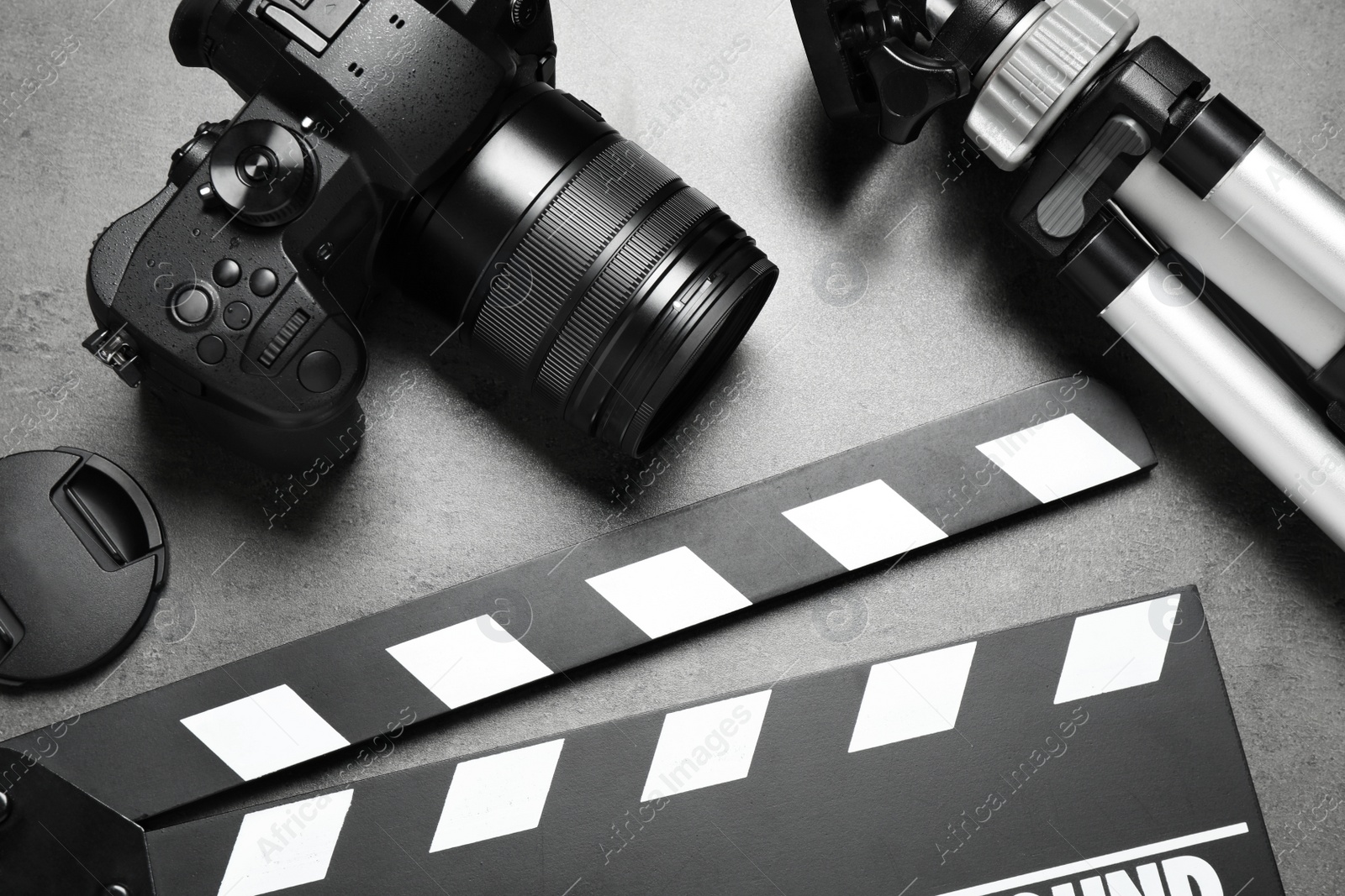 Photo of Clapboard with camera and tripod on grey background, flat lay. Video production industry