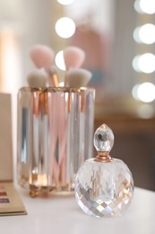 Photo of Bottle of perfume on white table in makeup room