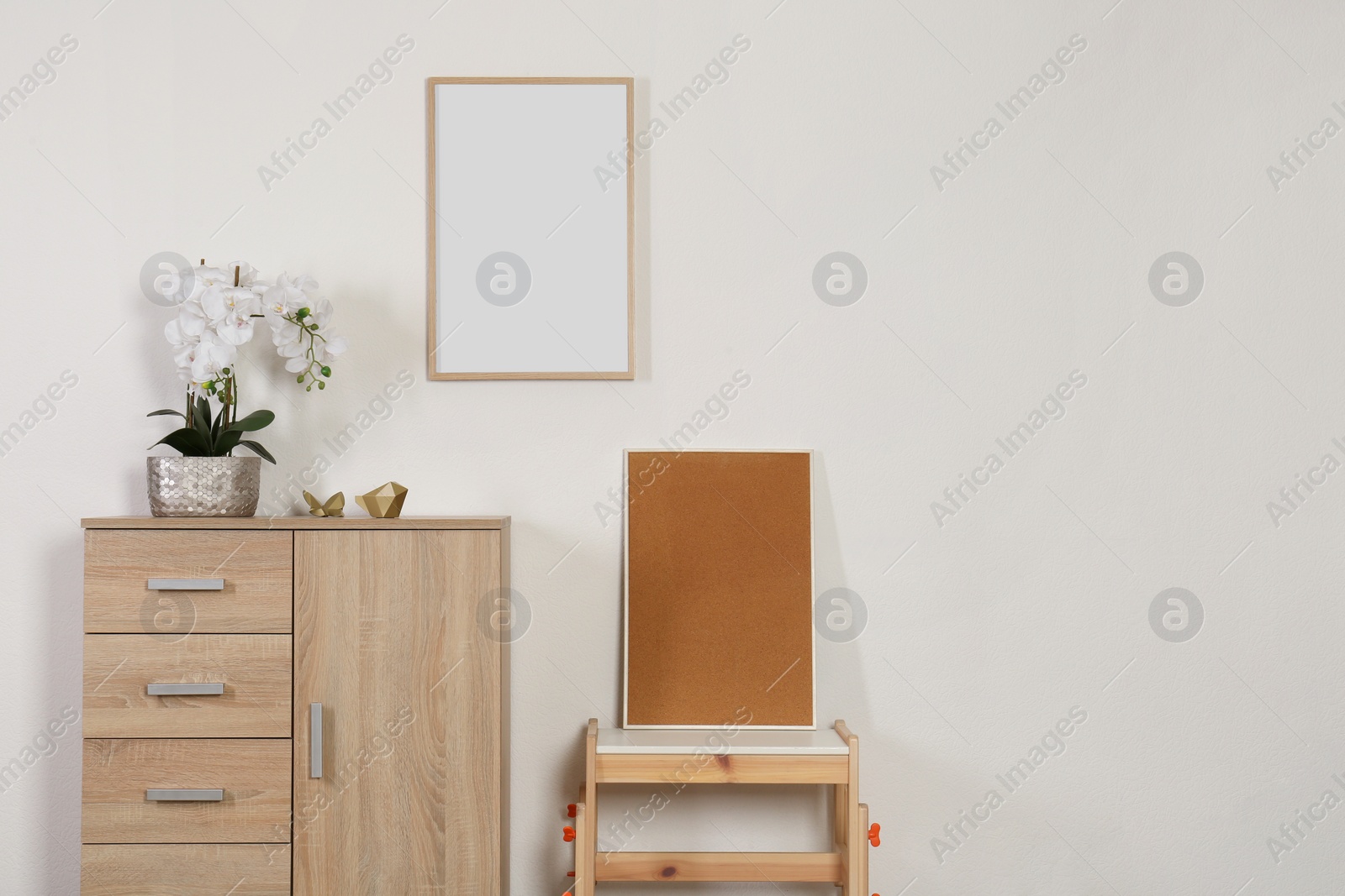 Photo of Chest of drawers, table, orchid and picture frames indoors, space for text. Interior design