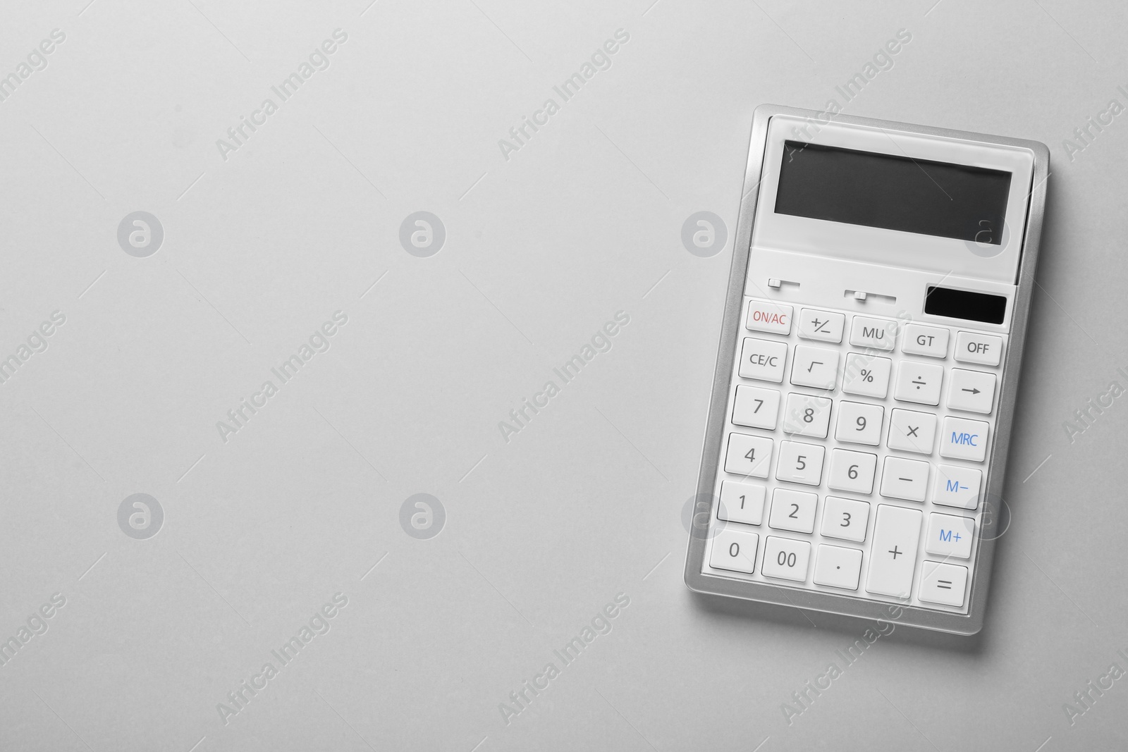 Photo of White calculator on light background, top view. Space for text