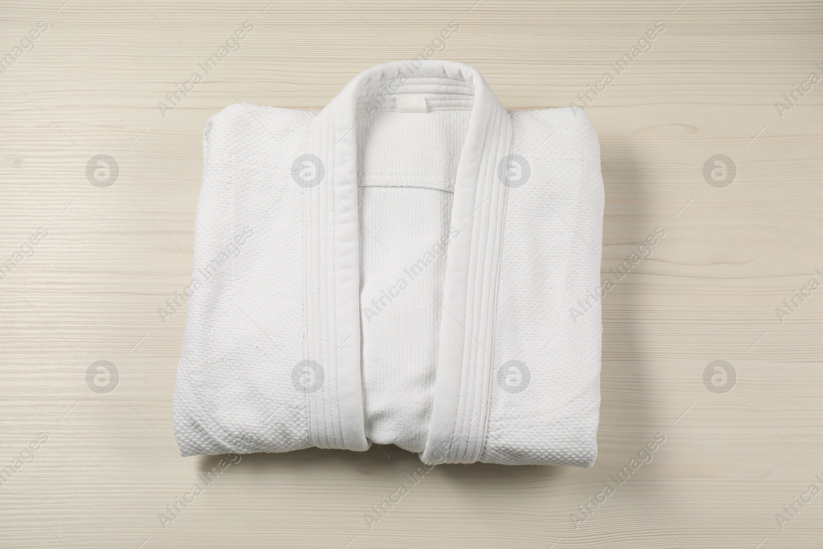 Photo of White kimono on wooden background, top view