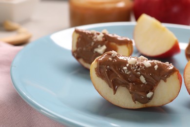 Photo of Slices of fresh apple with nut butter and chopped nuts on table, closeup