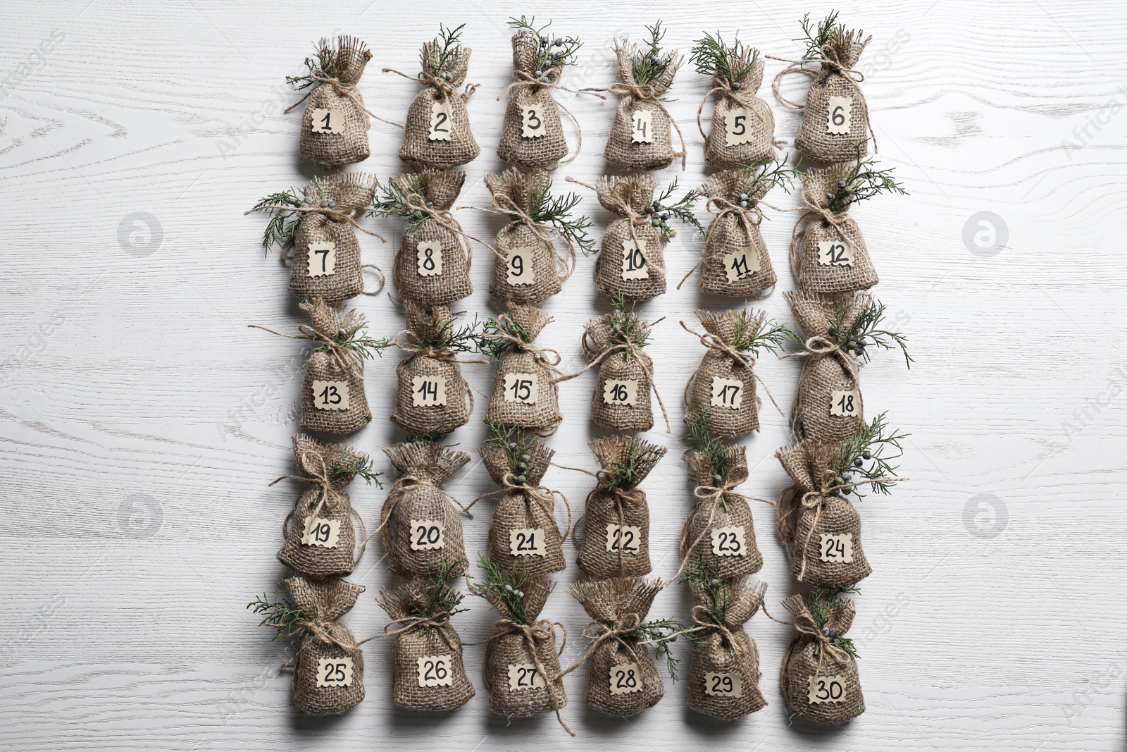 Photo of New Year advent calendar with gifts on white wooden background, flat lay