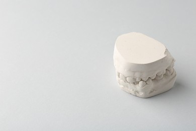 Photo of Dental model with gums on light grey background, space for text. Cast of teeth