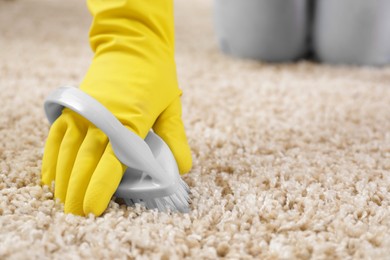 Photo of Woman cleaning carpet with brush indoors, closeup. Space for text