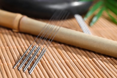 Photo of Many acupuncture needles on bamboo mat, closeup. Space for text