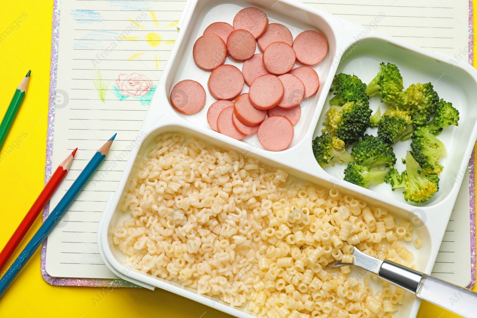 Photo of Section plate with tasty pasta, broccoli and sausage on yellow background, flat lay