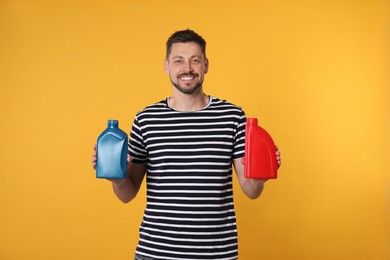 Man holding two containers of motor oil on orange background