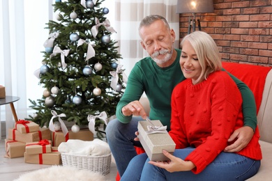 Mature couple with Christmas gift box at home