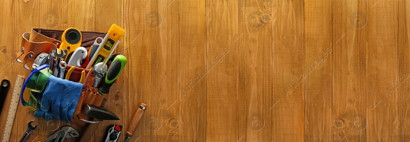 Image of Belt with different tools on wooden table, top view. Banner design with space for text