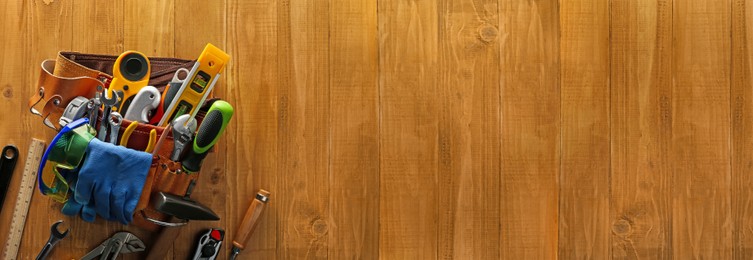 Image of Belt with different tools on wooden table, top view. Banner design with space for text