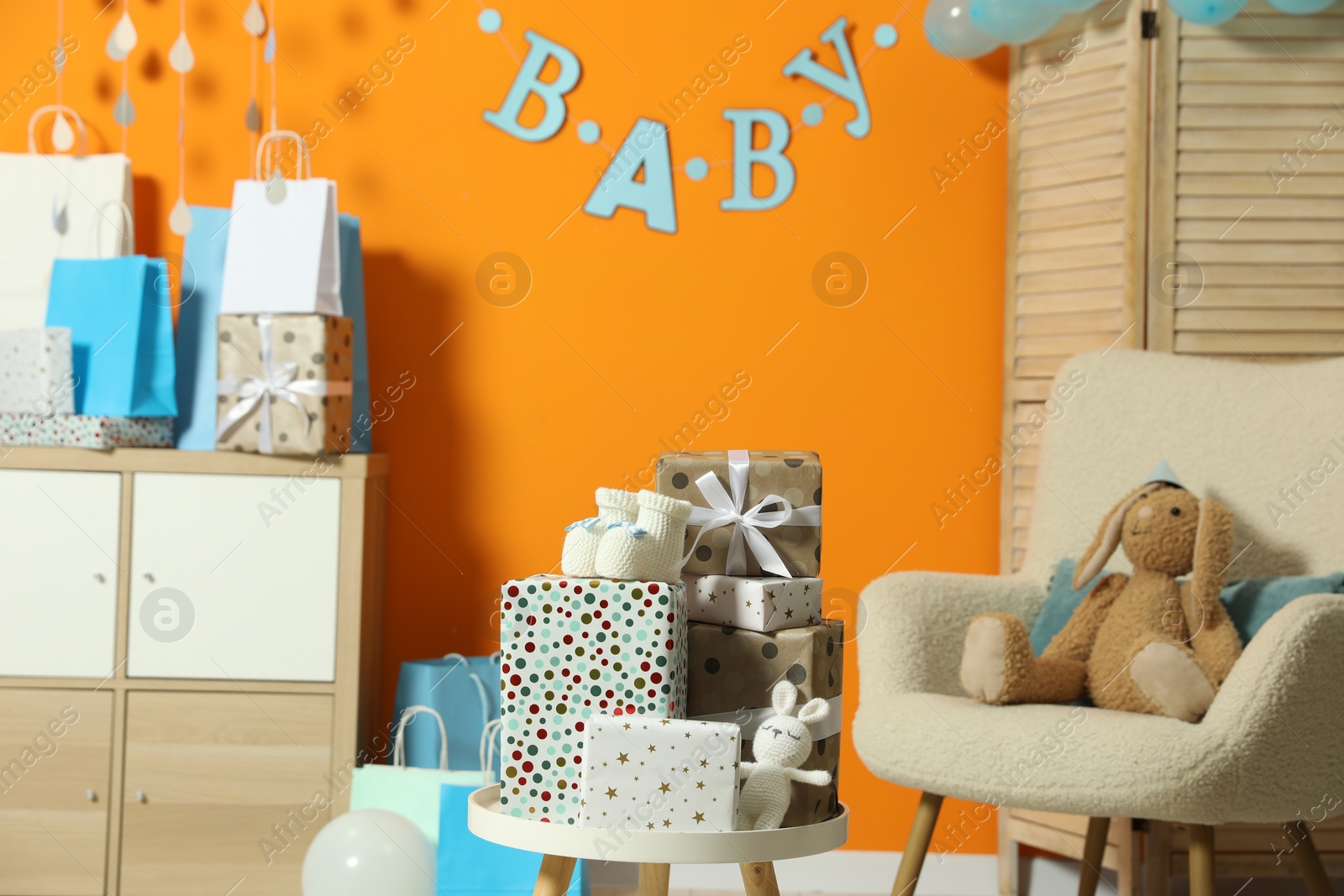 Photo of Baby shower party. Festive decor, gift boxes, booties and toys in stylish room