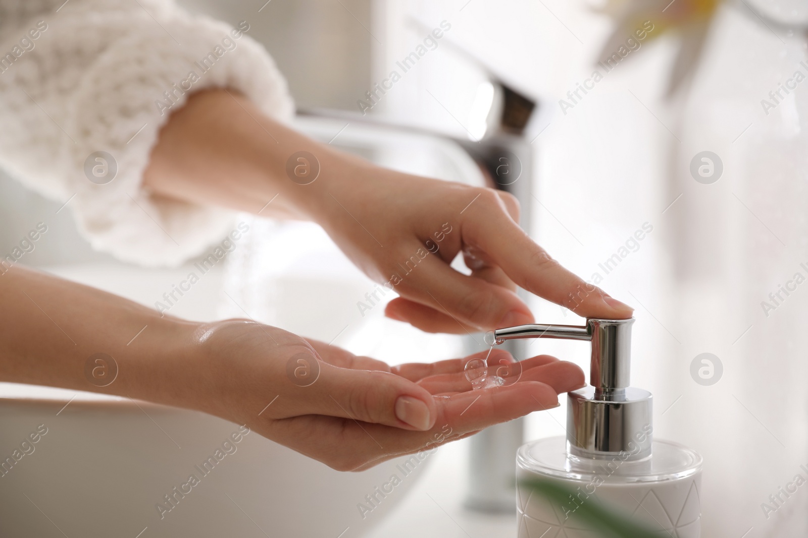 Photo of Woman using soap dispenser in bathroom, closeup