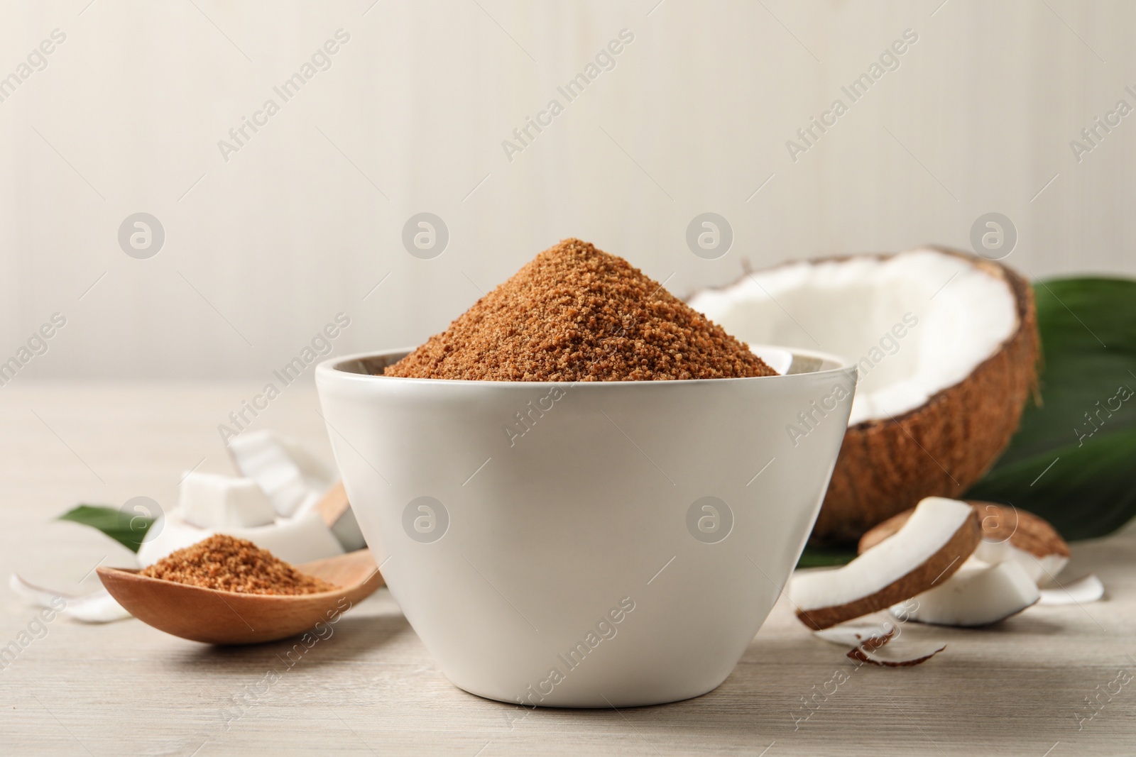 Photo of Natural coconut sugar in bowl on white wooden table