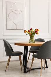 Vase with beautiful tulips on table in dining room