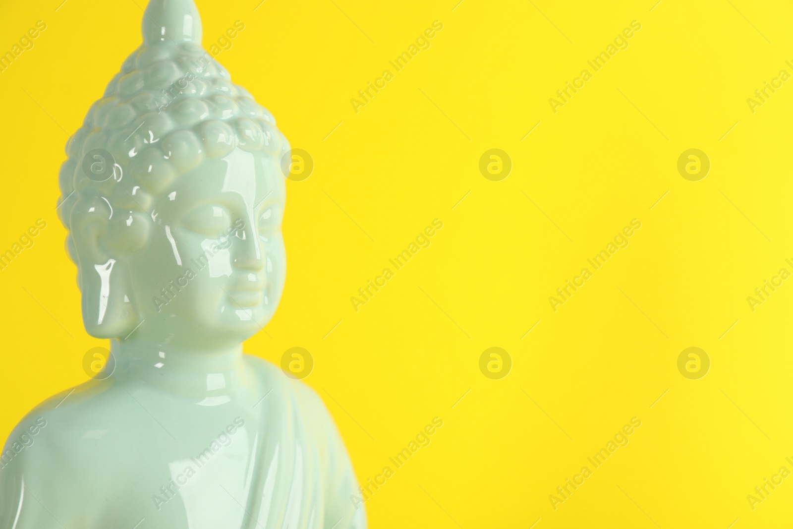 Photo of Beautiful ceramic Buddha sculpture on yellow background. Space for text