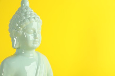 Photo of Beautiful ceramic Buddha sculpture on yellow background. Space for text