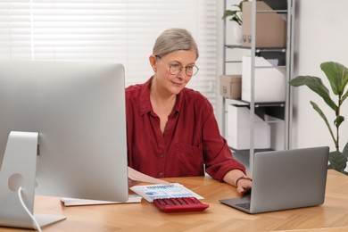 Senior accountant working at wooden desk in office