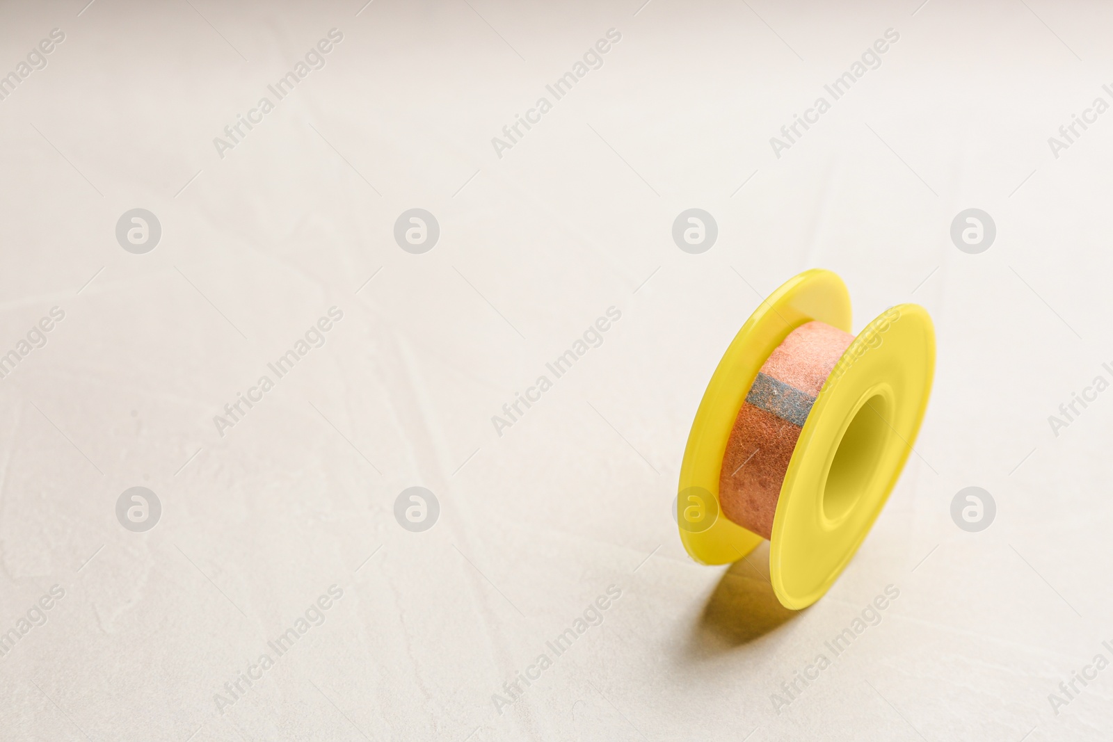 Photo of Sticking plaster roll on light stone background. Space for text