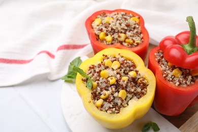 Photo of Quinoa stuffed bell peppers and basil on white table, closeup. Space for text