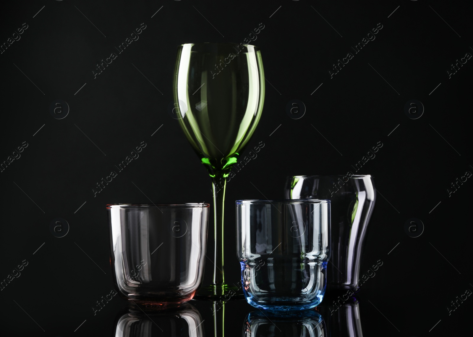 Photo of Set of different colorful empty glasses on black background