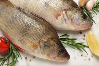Photo of Fresh raw perches and ingredients on white marble table, closeup. River fish