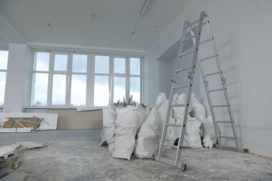 Used building materials and stepladder in room prepared for renovation