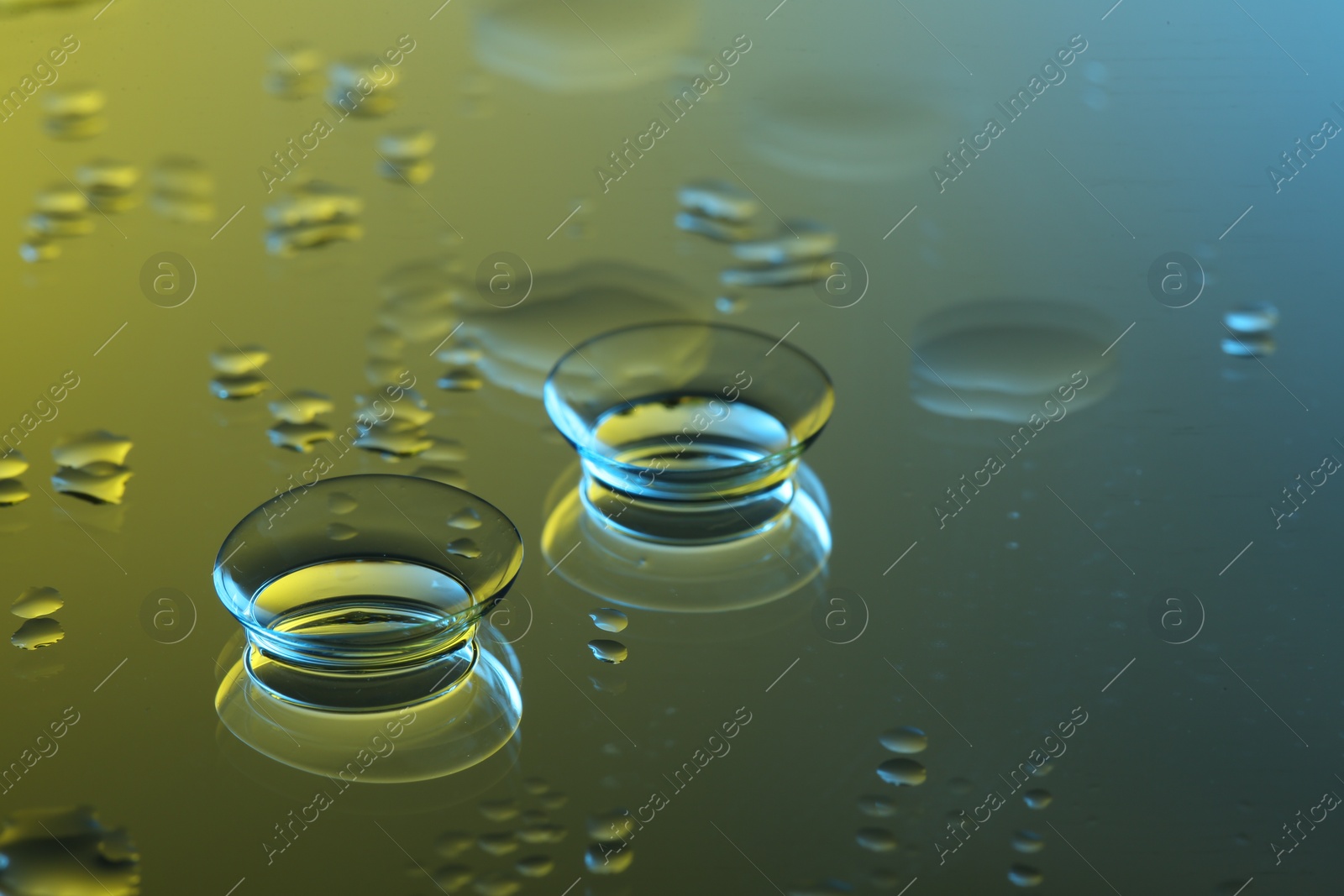 Photo of Pair of contact lenses on wet mirror surface. Space for text