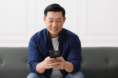 Photo of Portrait of smiling businessman with smartphone indoors
