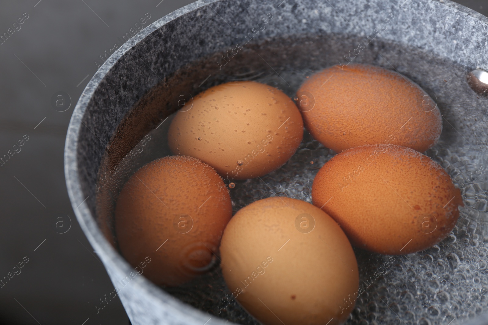 Photo of Chicken eggs boiling in saucepan on electric stove, closeup