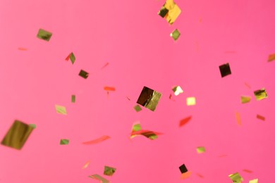 Photo of Shiny golden confetti falling down on pink background